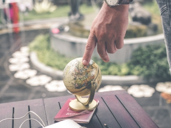 Person touching a small globe that is sitting on a park bench