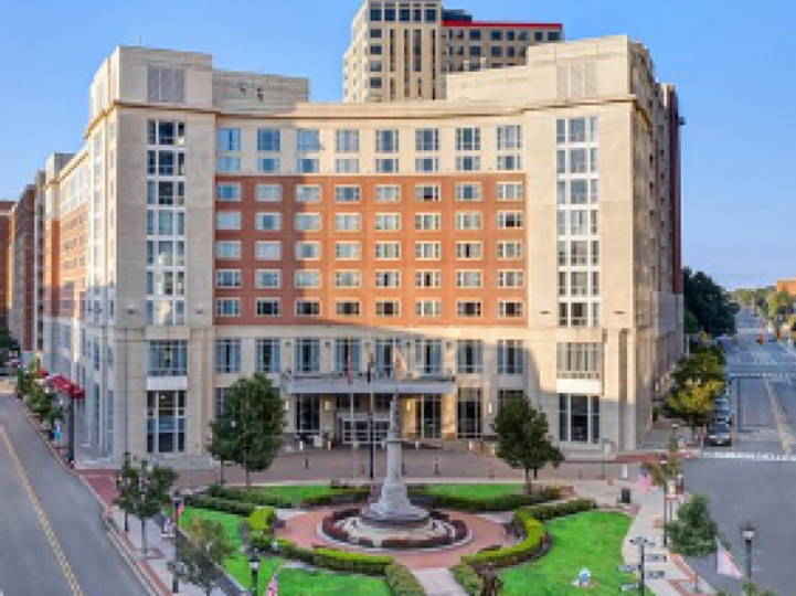 Multiple story building at an intersection with a lawn and fountain in front